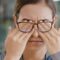 Frau mit Brille reibt sich die Augen zum Thema Glaskörpertrübung, Mouches volantes